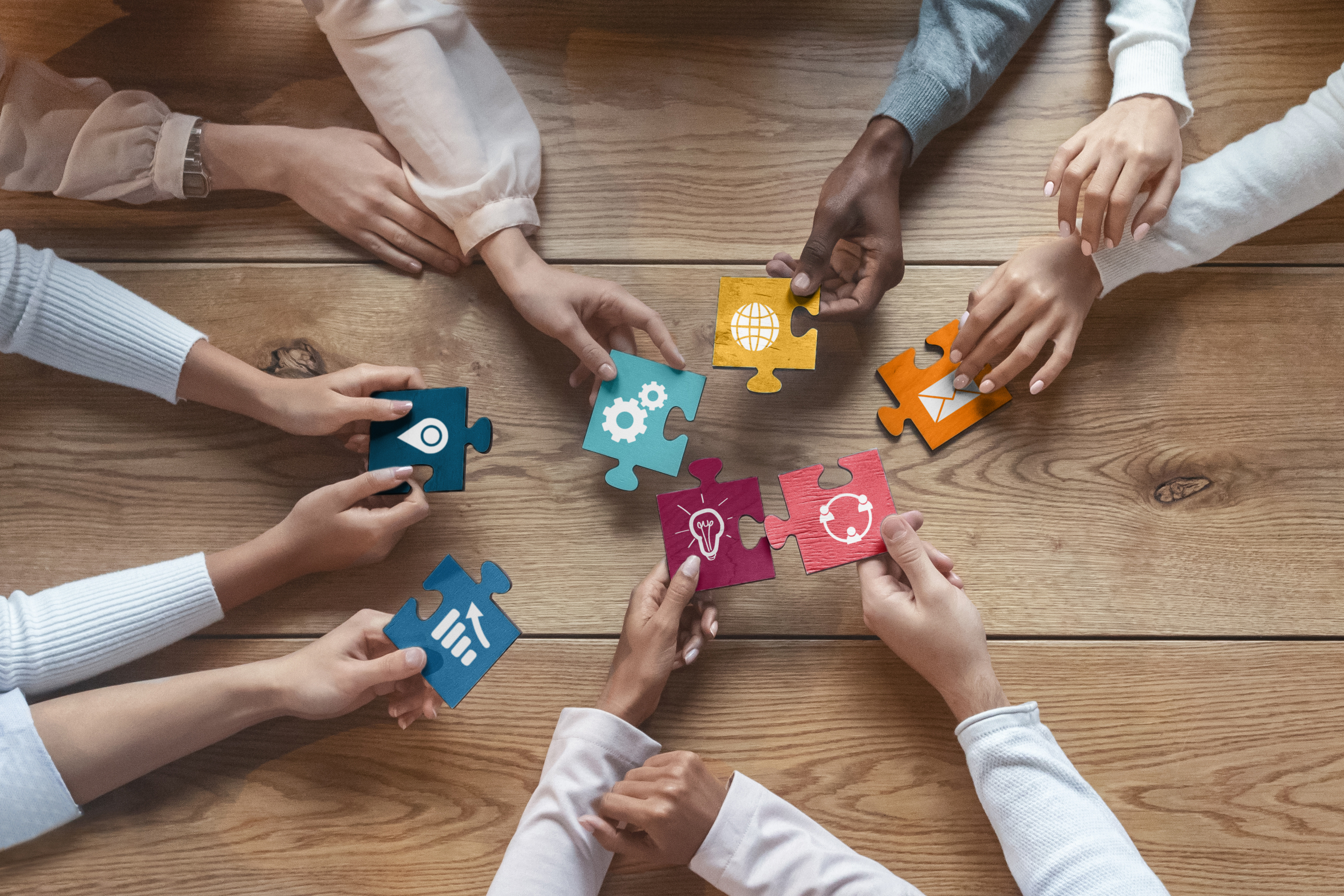 group of hands holding colorful puzzle pieces